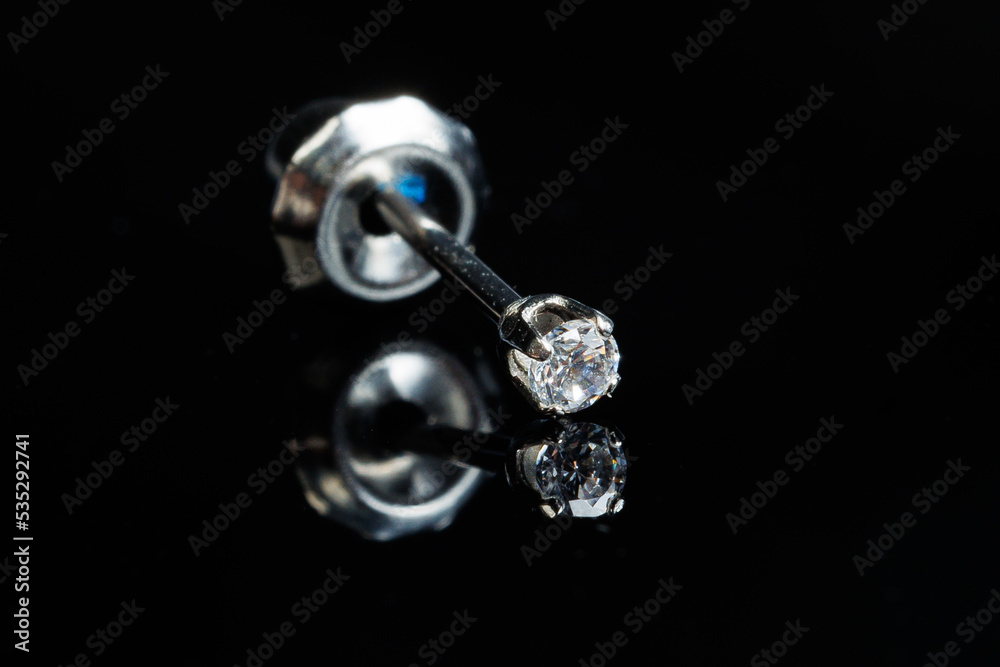 Silver earring macro photo with a precious stone on a black isolated background Silver earring macro photo with a precious stone on a black isolated background