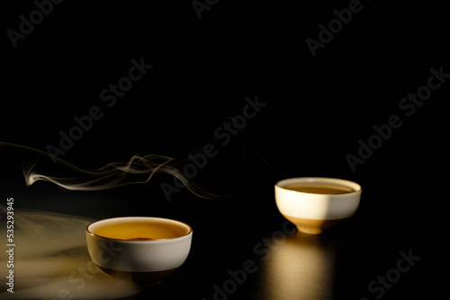 Two cups of chinese tea with steam isolated on black background. Top view