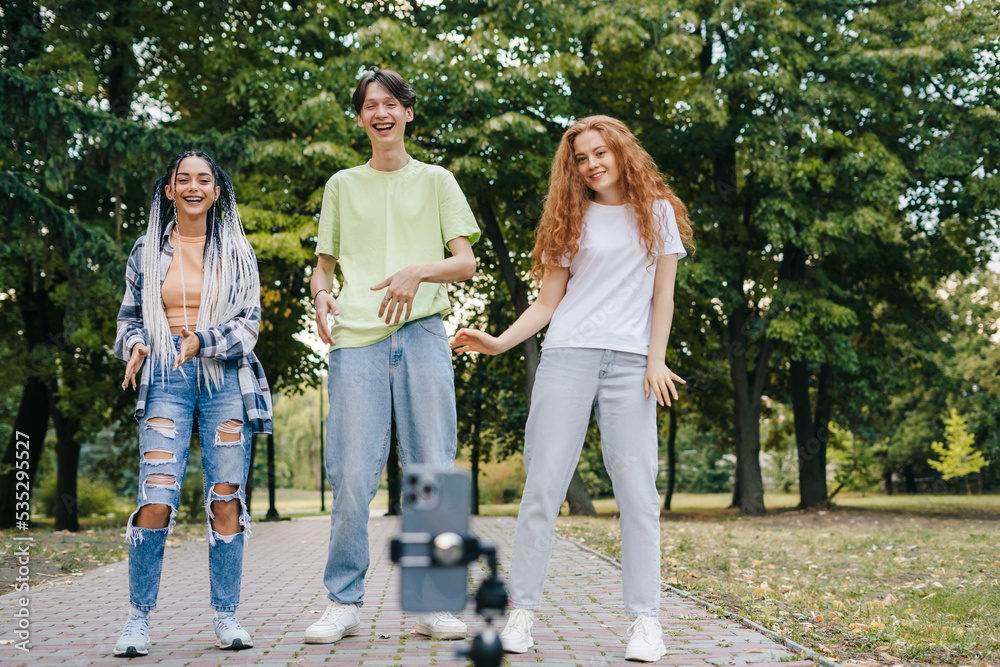 Social influencers creating online content for their channel, dancing in the city park. People and technology. Young group blogger. Web influencer recording Social influencers creating online content for their channel, dancing in the city park. People and technology. Young group blogger. Web influencer recording