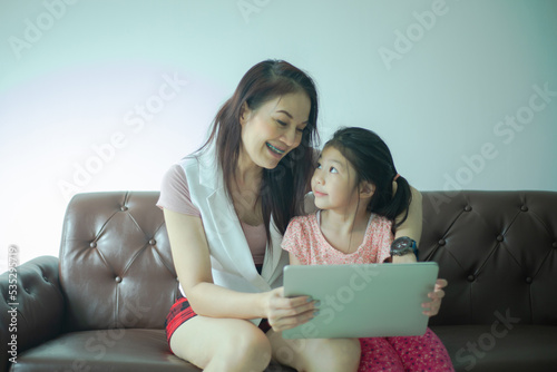 Asian mother teaching her kid to learn or study online with laptop computer.