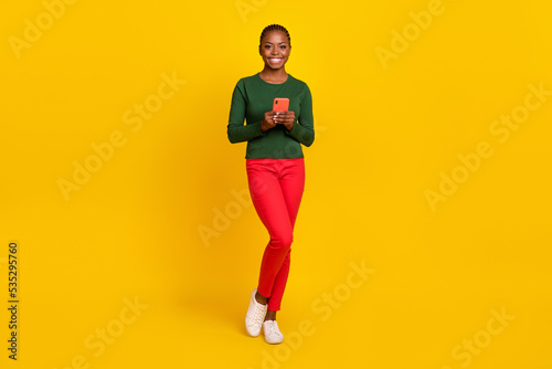 Full length photo of funky adorable woman wear green shirt typing modern device isolated yellow color background © deagreez