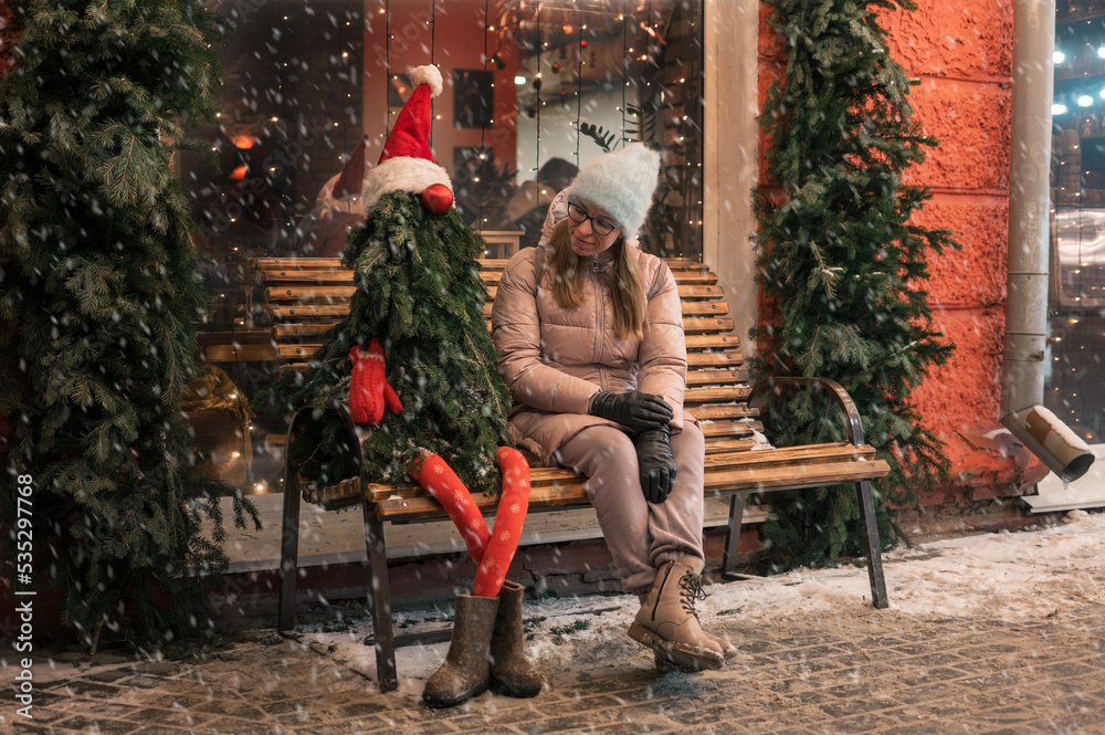 Obraz premium Pretty woman with fir tree decorated mannequin. Xmas holidays, New Year or Christmas concept