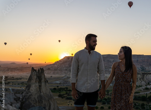 Young couple in love tourists at sunrise in Cappadocia with balloons in the sky