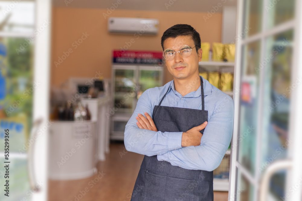 Obraz premium Smiling owner standing at his restaurant gate with open sign.