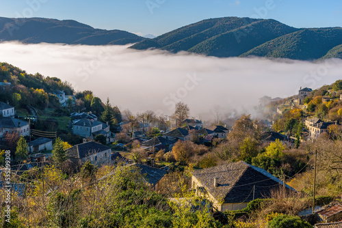View of the stone village Ano Pedina a misty  autumn morning with its architectural traditional old stone  buildings located on Tymfi mount, Zagori, Epirus, Greece, photo