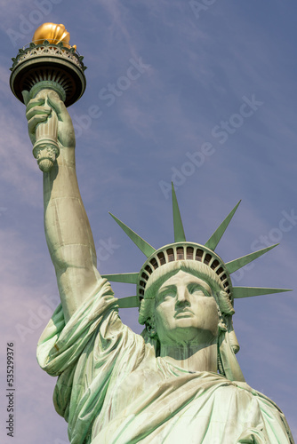 Close-up of the face, crown and hand holding the torch of the Statue of Liberty on a sunny day © SDF_QWE