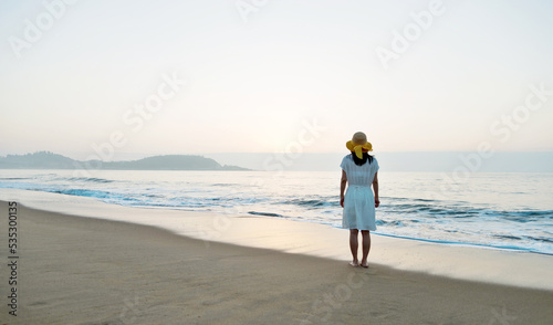 Young asian woman relaxing on the beach at sunrise. © xy