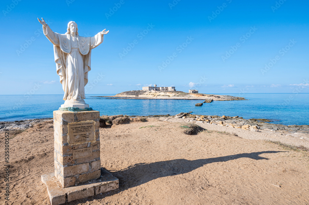 Φωτογραφία The statue of Christ Redeemer in Portopalo with the Island of Correnti in backgr
