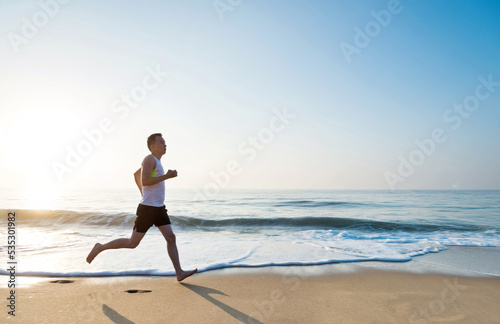 Young man running along beach in the morning