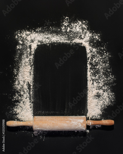 Flour with rolling pin on dark gray background