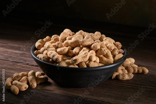 Dried peanuts in a bowl on a wooden table.