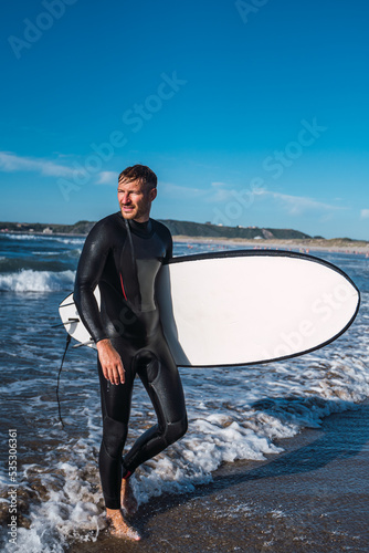 Obraz na płótnie Man coming out of the sea after an afternoon doing his favorite sport. Surf w salonie