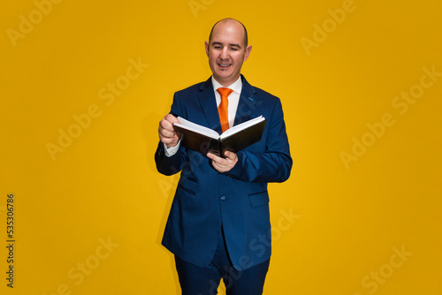Well-dressed bald man reading a book