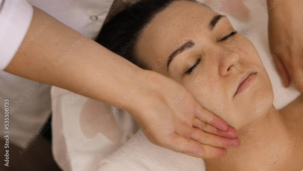 Woman receiving facial massage in beauty salon.Beauty and skincare concept with a beautiful woman. Middle aged female relaxed with massage for facial lifting Woman receiving facial massage in beauty salon.Beauty and skincare concept with a beautiful woman. Middle aged female relaxed with massage for facial lifting