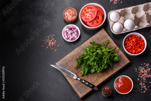 Ingredients for making shakshuka, dishes with fried eggs with tomato sauce, spices and herbs