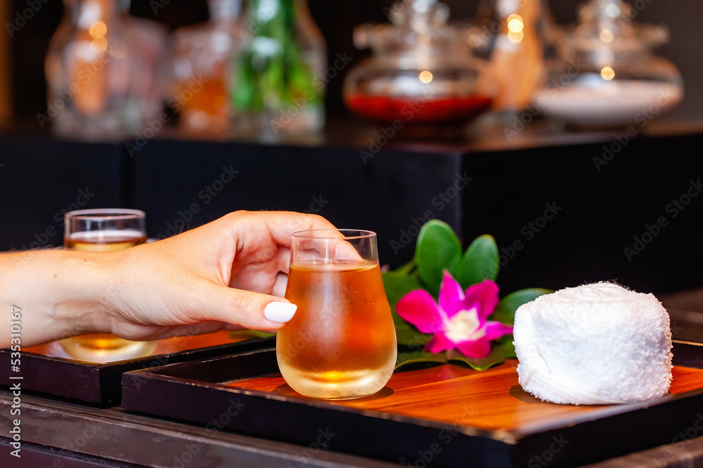 Woman hand take a herbal spa tea in a glass cup