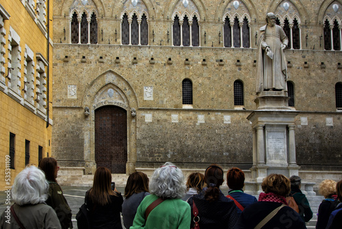 Old people visit Salimbeni square in Siena Tuscany Italy where the Monte dei Paschi di Siena bank is located photo