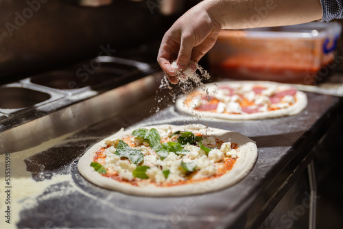 Pizza making process. Male chef hands making authentic pizza in the pizzeria kitchen. photo