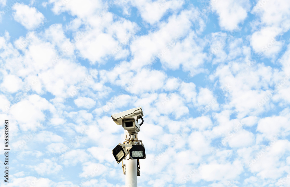 Security cameras under cloud sky