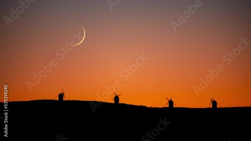 Timelapse of the crescent moon setting behind the iconic Consuegra windmills in Spain