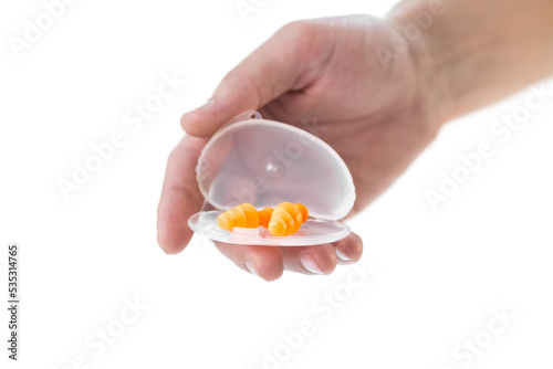 The hand holds bright earplugs on a white background