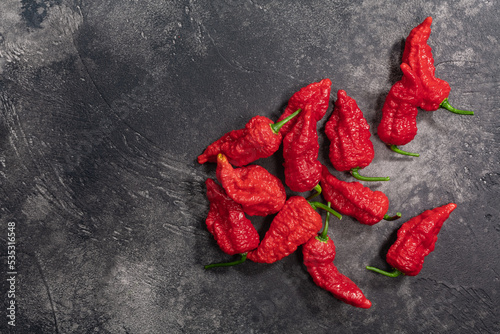 Bhut Jolokia peppers atop dark textured backdrop, top view, copy space. Ghost chile peppers, a Capsicum chinense fruits