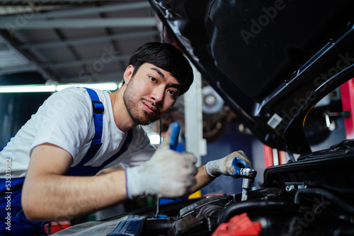 Male mechanic checking the engine system in the car, service, maintenance. Auto mechanic repairing engine. A mechanic is fixing the engine of a car at his factory. Concept of auto service