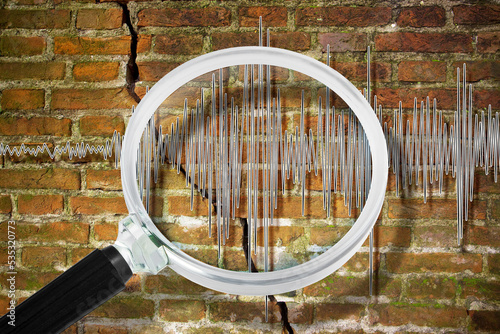 Earthquake wave graph concept with cracked and damaged brick wall and magnifying glass photo