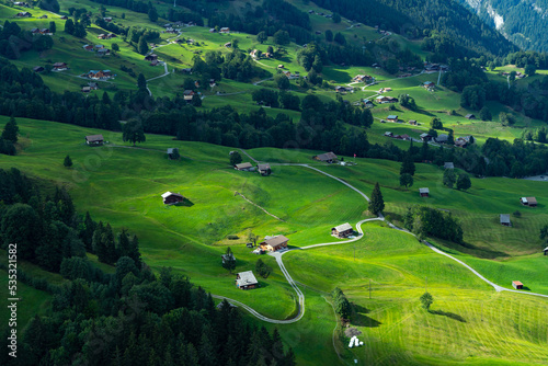 Stunning view of Grindelwald Valley in summer with golden sunshine on green grass. Heavenly beauty village in Switzerland.