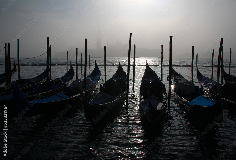 Moored gondolas in front of San Giorgio Maggiore made ghostly by fog on a freezing late December morning (Venice, Italy).