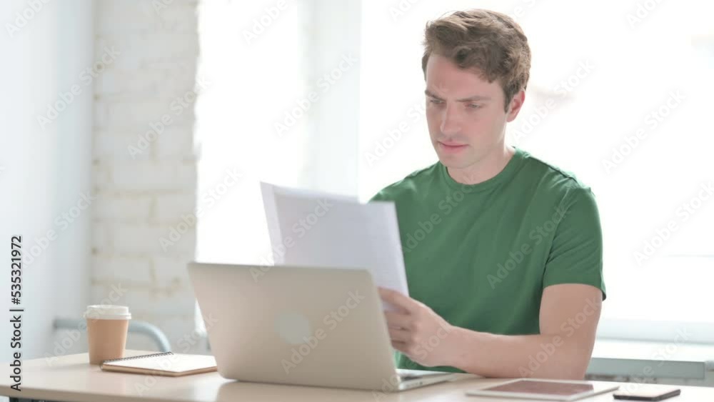 Young Man Working on Laptop and Documents Young Man Working on Laptop and Documents