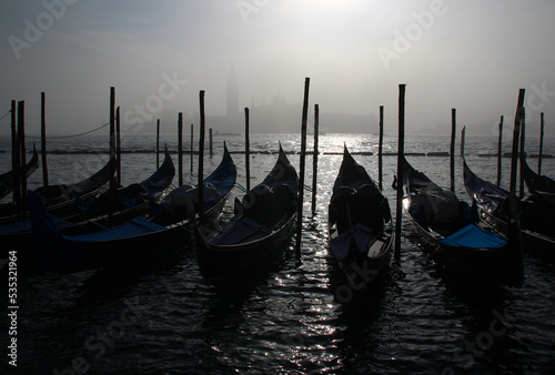 Moored gondolas in front of San Giorgio Maggiore made ghostly by fog on a freezing late December morning (Venice, Italy).