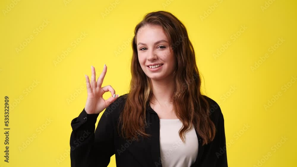 4k video of smiling woman showing ok sign on yellow background. 4k video of smiling woman showing ok sign on yellow background.