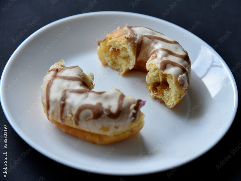 Delicious sweet donuts on a white plate. Donuts in glaze with filling close-up.