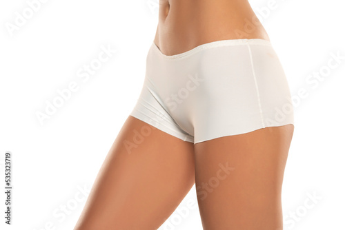 Mid section of woman wearing white briefs, side view on a white background.