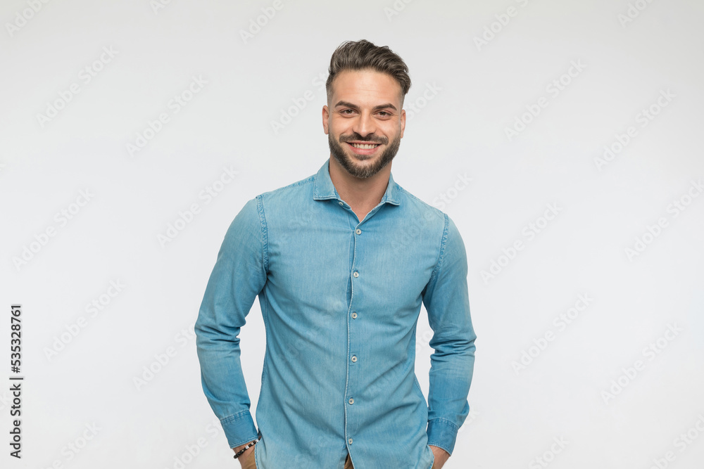 casual man holding hands in pockets with a big smile casual man holding hands in pockets with a big smile