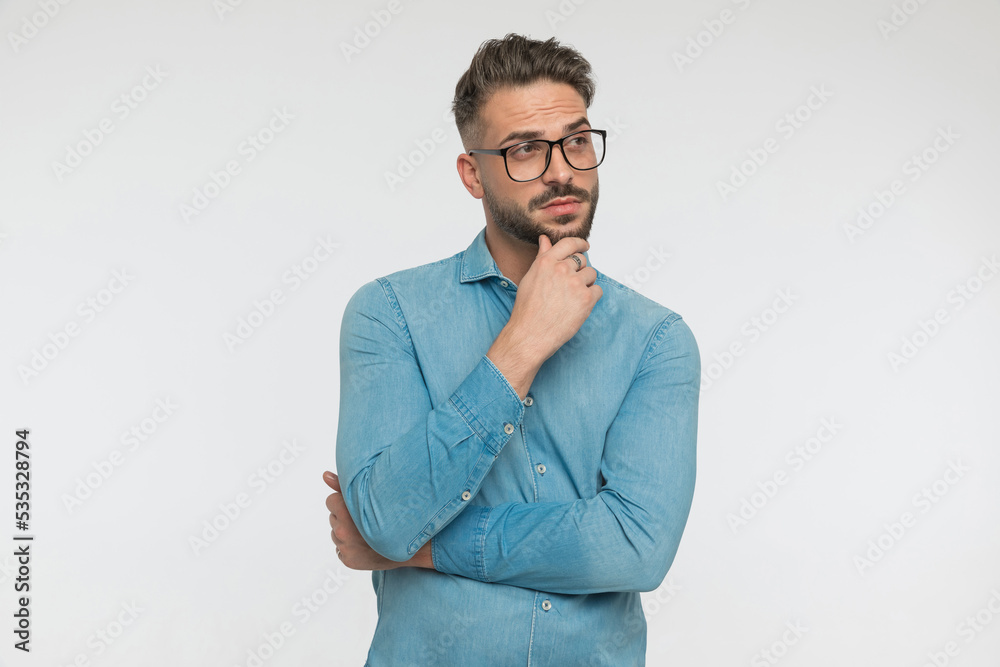 young casual man scratching his chin, looking away young casual man scratching his chin, looking away