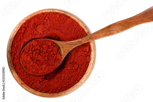 Top view of a wooden bowl with smoked paprika and a wooden spoon.
