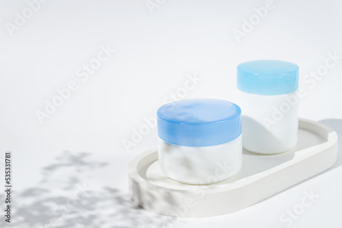 Set of day and night cream jars on a concrete tray on white background with flowers chados. Skin care concept, Mockup