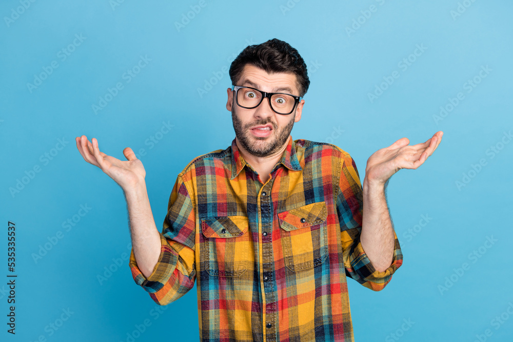 Naklejka premium Photo of handsome young confused guy in eyewear dressed plaid shirt question shrugging shoulders isolated on blue color background