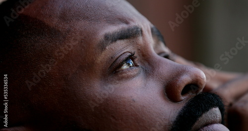 Pensive worried black African man close-up eyes looking up to sky seeking God help