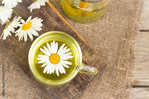 chamomile tea is a therapeutic healthy drink a cup against the background of daisies A lot of daisies on the table Copy space