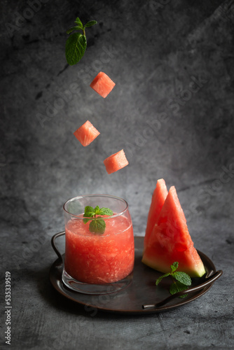 Mint, ripe watermelon, refreshing watermelon juice on a dark background.