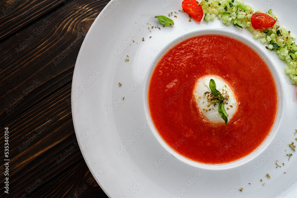 Tomato soup in a white plate on a wooden background Tomato soup in a white plate on a wooden background