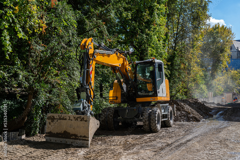Yellow excavator standing on the side of a dirt road. Yellow excavator standing on the side of a dirt road.