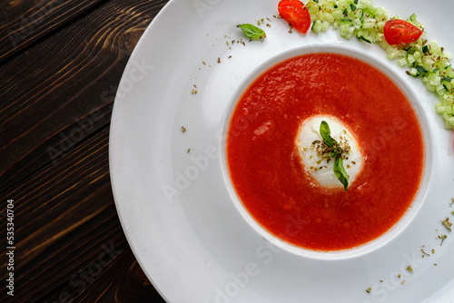 Tomato soup in a white plate on a wooden background