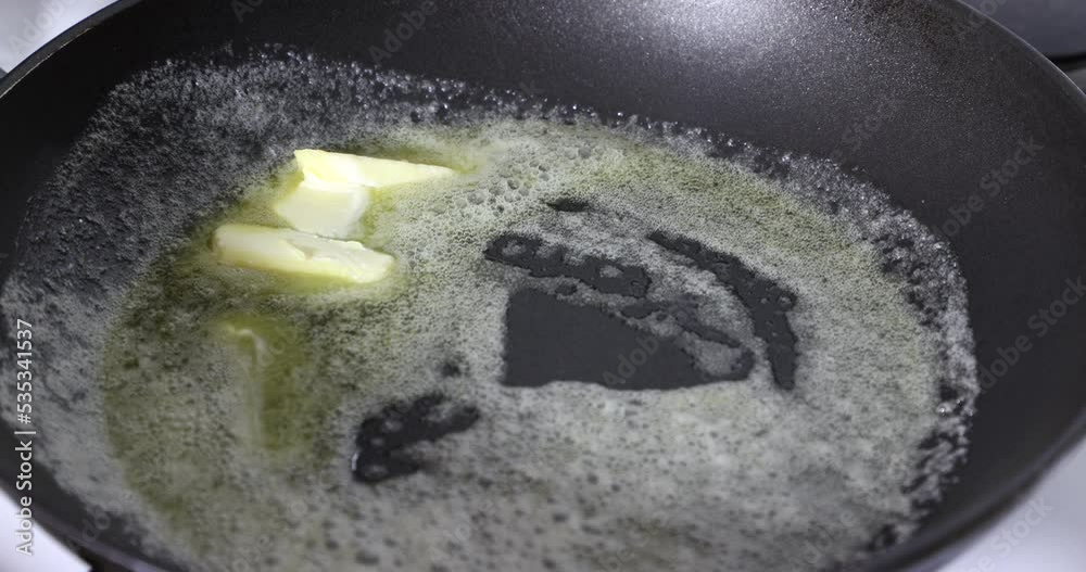 Piece of butter melting in a frying pan, beginning to melt slowly, gas
