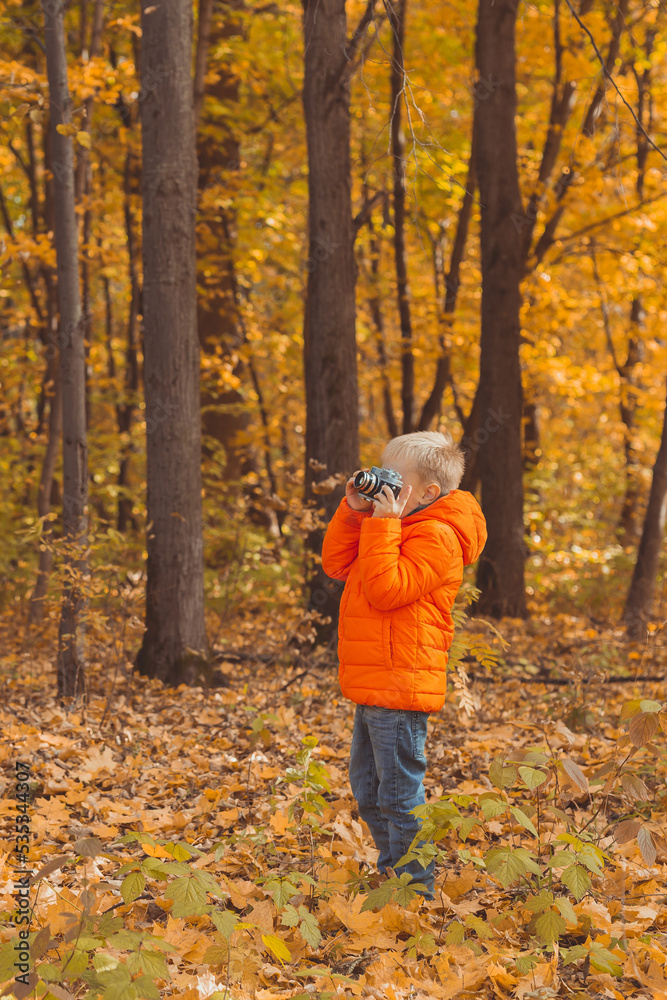 Boy with retro camera taking pictures outdoor in autumn nature. Leisure and photographers concept Boy with retro camera taking pictures outdoor in autumn nature. Leisure and photographers concept