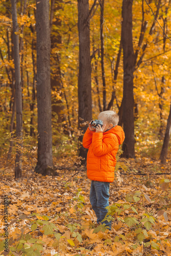 Boy with retro camera taking pictures outdoor in autumn nature. Leisure and photographers concept © satura_