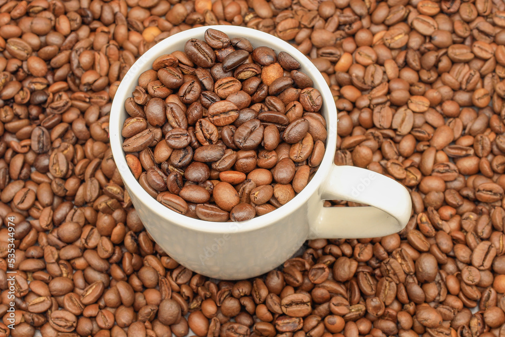 White cup filled with coffee beans on rustic wooden table. Top view. Coffee concept for cafes White cup filled with coffee beans on rustic wooden table. Top view. Coffee concept for cafes